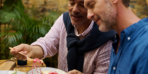Two men smiling at a barbeque  Two men smiling at a barbeque